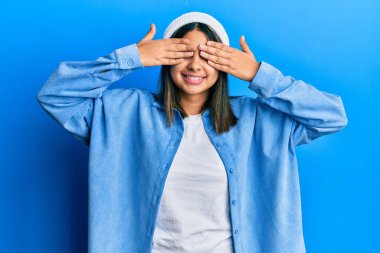 Şirin yün şapka takan, elleri gülücüklü, neşeli gözlü genç Latin bir kadın. kör kavram. 