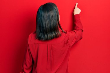 Orta yaşlı İspanyol kadın, gündelik giysiler giymiş, geriye doğru poz veriyor, parmağıyla ileri işaret ediyor. 