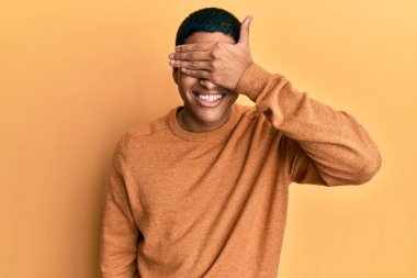 Genç, yakışıklı, sıradan bir süveter giyen, gülümseyen ve gözlerini kapayarak şaşıran İspanyol bir adam. kör kavram. 