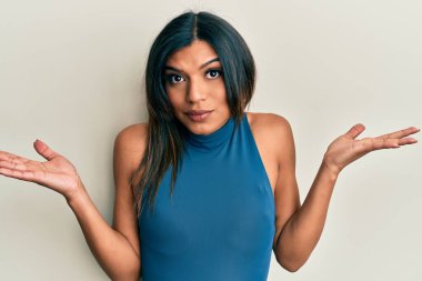 Genç Latin transseksüel kadın gündelik giysiler giyiyor, habersiz ve kolları açık, hiçbir fikrim yok ve şüpheli bir yüzüm var.. 