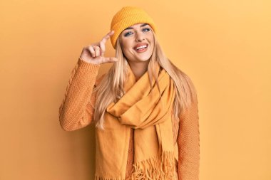 Beyaz kadın yün kazak ve kep giyen, gülümseyen, kendine güvenen, el hareketi yapan, parmaklarıyla işaret yapan ve kameraya bakan. ölçüm kavramı. 