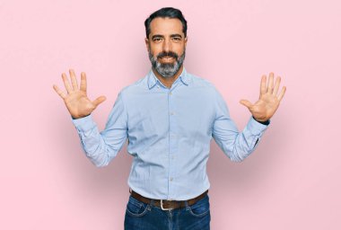 Sakallı, iş gömleği giyen orta yaşlı bir adam on numarayı gösteriyor ve gülümsüyor. Kendinden emin ve mutlu.. 