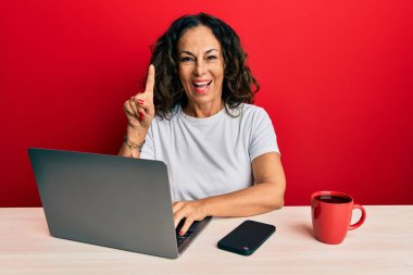 Ofiste çalışan orta yaşlı güzel bir kadın bir fikir ya da soruyla şaşırmış, mutlu bir yüzle işaret ediyor. 