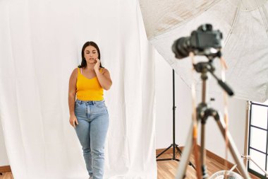 Fotoğraf stüdyosunda mankenlik yapan genç ve güzel bir İspanyol kadın diş ağrısı ya da diş ağrısı yüzünden acı dolu bir ifadeyle ağıza dokunuyor. dişçi 