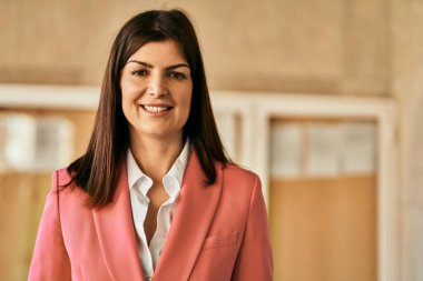 Zarif bir ceket giyen güzel İspanyol iş kadını şehirde mutlu bir şekilde gülümsüyor.