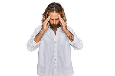 Sakallı, uzun saçlı, başı ağrıyan ve stresten başı ağrıyan sıradan kıyafetler giyen yakışıklı bir adam. migren ağrısı. 