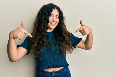 Genç esmer, kıvırcık saçlı, günlük kıyafetler giyen, kendine güvenen, gülümseyen, kendini gururlu ve mutlu gösteren bir kadın.. 