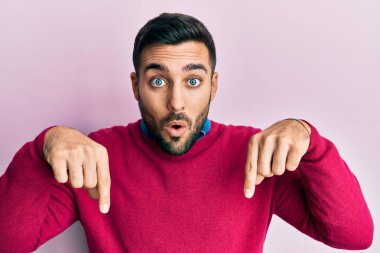 Gündelik giysiler giymiş genç İspanyol bir adam parmaklarını göstererek reklamını yapıyor, şaşırmış bir yüz ve ağzını açıyor. 