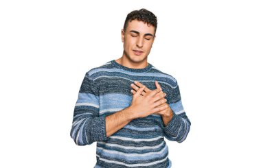 Latin asıllı genç adam gündelik kıyafetler giyiyor elleri göğsünde, gözleri kapalı gülümsüyor ve yüzünde minnet ifadesi var. sağlık kavramı. 