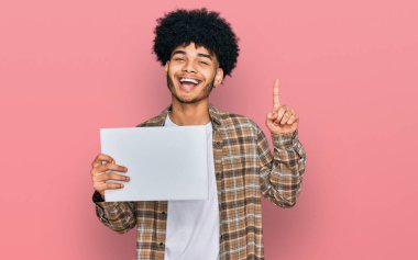 Afro saçlı, boş afiş taşıyan genç Afrikalı Amerikalı bir adam bir fikir ya da soru işareti ile şaşırdı. 