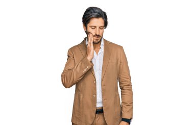 İş kıyafetleri giymiş genç İspanyol bir adam diş ağrısı ya da diş hastalığından dolayı acı dolu bir ifadeyle ağıza dokunuyor. dişçi 