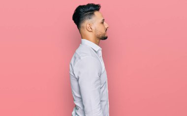 Gündelik giysiler giyen genç bir Arap, rahat bir görünüm takınıyor, kendine güvenen bir gülümsemeyle doğal bir yüz ifadesi sergiliyor.. 