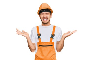 Tamirci üniforması giyen İspanyol genç adam ve emniyet kaskı takan çılgın ve başarıyı kollarını kaldırmış ve gözleri kapalı heyecanla haykırarak kutluyor. Kazanan konsept 