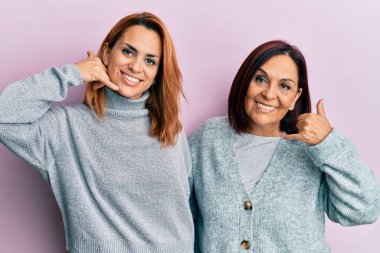 Latin anne ve kız günlük kıyafetler giyip gülümsüyor telefonla el ve parmaklarıyla jest yapıyor telefonda konuşuyor gibi. iletişim kavramları. 