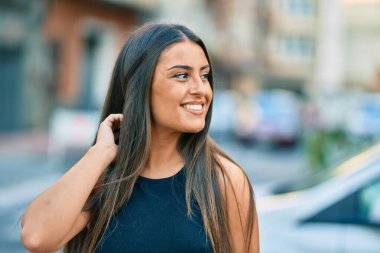 Genç İspanyol kız gülümseyerek şehirde mutlu mesut dikiliyor..