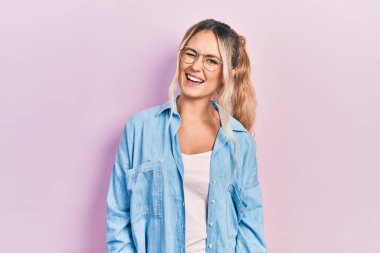 Güzel, genç, sarışın bir kadın. Günlük kıyafetler ve gözlük takıyor. Seksi bir ifadeyle, neşeli ve mutlu bir yüzle kameraya bakıyor.. 