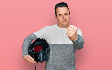 Motosiklet kaskı tutan yakışıklı genç adam öfkeyle bağırıyor, öfkeyle bağırıyor ve el kaldırıyor. 