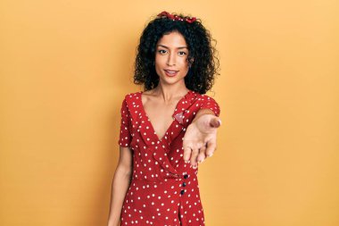 Yazlık elbise giyen, neşeli gülümseyen, yardım eli uzatan ve kabul gören genç Latin kız.. 