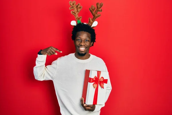 Mladý Africký Američan Nosí Jelení Vánoční Klobouk Drží Dárek Vypadá — Stock fotografie