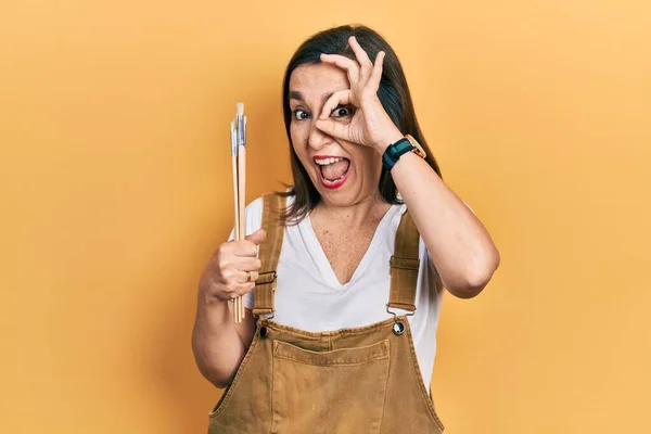 Mulher Hispânica Meia Idade Segurando Pincéis Sorrindo Feliz Fazendo Sinal — Fotografia de Stock