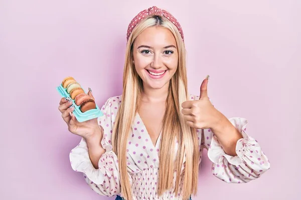Menina Loira Jovem Segurando Deliciosos Macarons Doces Sorrindo Feliz Positivo — Fotografia de Stock