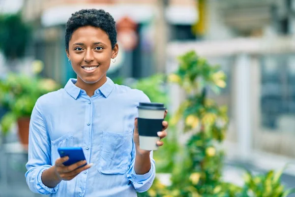 若いアフリカ系アメリカ人の少女がスマートフォンを使い街でコーヒーを飲みながら — ストック写真