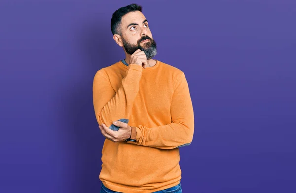 一个留着胡子的西班牙男人 穿着宽松的冬季毛衣 手放在下巴上思考着问题 沉思着表情 微笑和体贴的脸 怀疑概念 — 图库照片