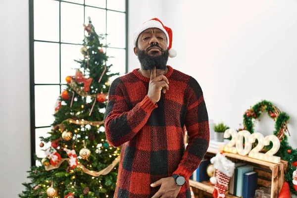 Afrikanischer Mann Mit Weihnachtsmannmütze Steht Weihnachtsbaum Und Denkt Konzentriert Mit — Stockfoto