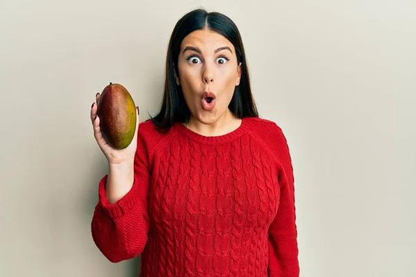 Beautiful Brunette Woman Holding Mango Scared Amazed Open Mouth Surprise — Stock Photo, Image