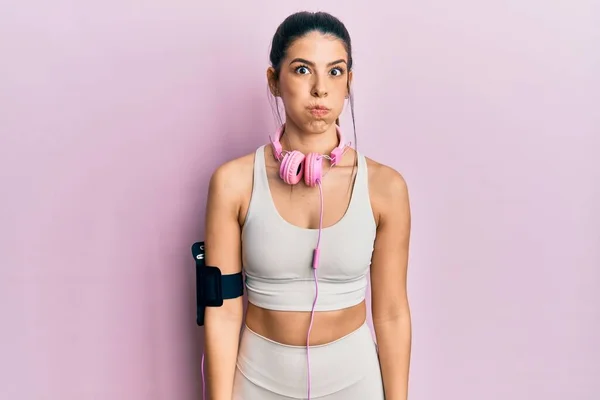 Mujer Hispana Joven Usando Ropa Gimnasia Usando Auriculares Hinchando Mejillas — Foto de Stock