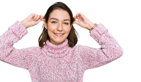 若い白人の少女は 指で耳を引く笑みを浮かべてウールの冬のセーターを着て 面白いジェスチャー オーディション問題 — ストック写真