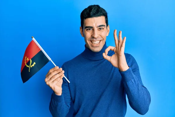 Bonito Hispânico Homem Segurando Bandeira Angola Fazendo Sinal Com Dedos — Fotografia de Stock