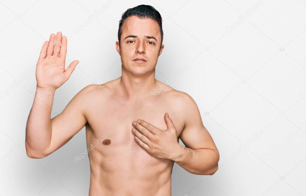 Handsome young man wearing swimwear shirtless swearing with hand on chest and open palm, making a loyalty promise oath 