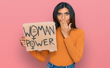 Genç Latin transseksüel kadın elinde kadın güç pankartı ile ağzını eliyle kapatıyor, şaşırmış ve hata yapmaktan korkuyor. şaşırmış ifade 