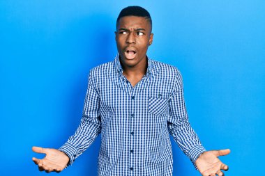 Genç, Afro-Amerikalı, günlük kıyafetler giymiş çılgın ve kızgın bir şekilde bağırıyor, agresif bir ifade ve kollarla bağırıyor. hüsran kavramı. 