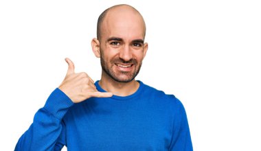 Günlük kıyafetler giymiş, gülümseyen genç İspanyol adam telefonla el ve parmak hareketleri yapıyor telefonda konuşur gibi. iletişim kavramları. 