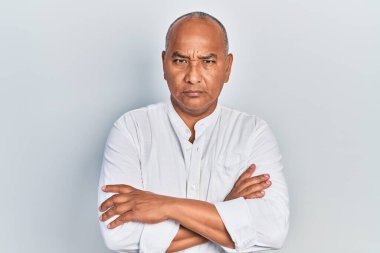 Orta yaşlı, sıradan kıyafetler giyen, kuşkucu ve gergin, yüzünde çapraz kollu tasvip etmeyen bir ifade. negatif kişi. 