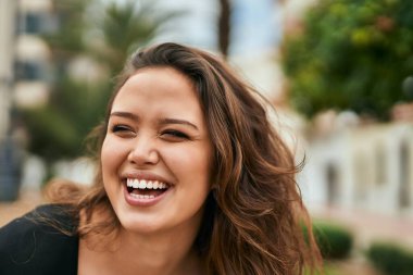 Genç İspanyol kadın gülümseyerek şehirde mutlu mesut dikiliyor..