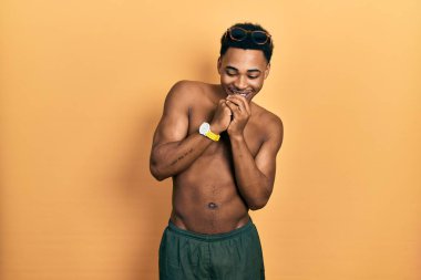 Mayo ve yüzme gözlüğü takan genç Afro-Amerikalı adam elleri çenesinde gergin ve heyecanlı bir şekilde yan tarafa bakıyor. 