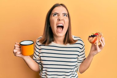 Genç ve güzel bir kadın kahve içiyor ve pasta yiyor kızgın ve kızgın çığlık atıyor hayal kırıklığına uğramış ve öfkeli, öfkeyle bağırıyor.. 
