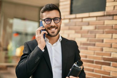 Genç İspanyol işadamı gülümsüyor. Şehirdeki akıllı telefondan mutlu bir şekilde konuşuyor..
