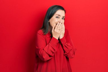 Orta yaşlı İspanyol kadın gündelik kıyafetler giyip gülüyor ve utanıyor kıkırdıyor elleriyle ağzını kapatıyor, dedikodu yapıyor ve skandal konsepti yapıyor. 