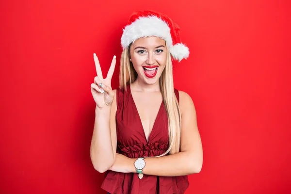 Genç Sarışın Kız Noel Şapkası Takıyor Gülümsüyor Kameraya Göz Kırpıyor — Stok fotoğraf