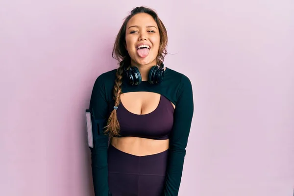 Junges Hispanisches Mädchen Sportkleidung Und Kopfhörer Die Die Zunge Herausstrecken — Stockfoto