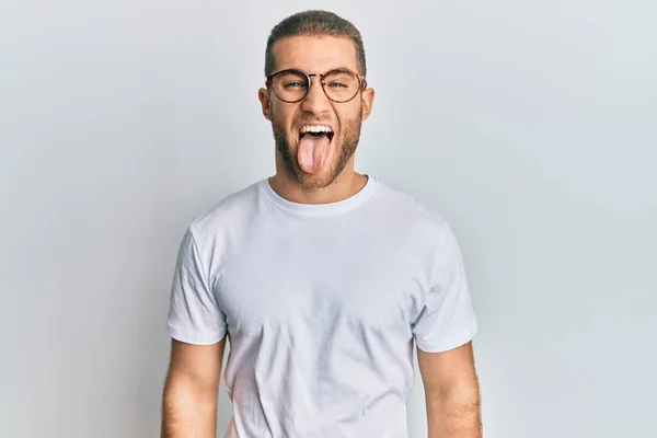 カジュアルな服を着た若い白人男性と面白い表情で幸せ舌を突き出す眼鏡 感情の概念 — ストック写真