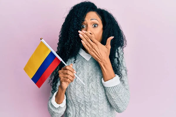 Afroameričanka Středního Věku Držící Kolumbijskou Vlajku Ústech Šokovaná Vystrašená Omylu — Stock fotografie
