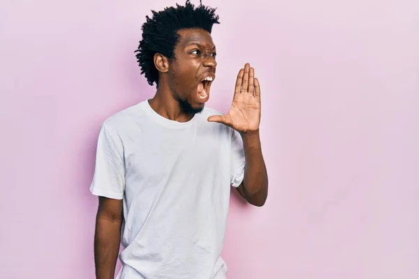 若いアフリカ系アメリカ人の男性は カジュアルな白いTシャツを着て大声で叫び 口の上に手で横に叫んでいます コミュニケーションの概念 — ストック写真