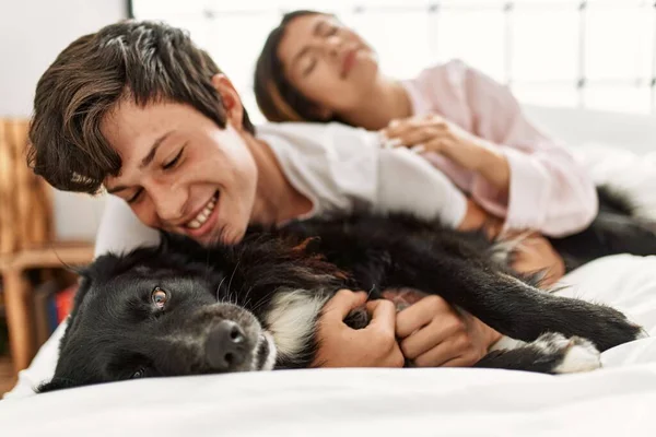 Jovem Casal Caucasiano Sorrindo Feliz Deitado Cama Brincando Com Cão — Fotografia de Stock