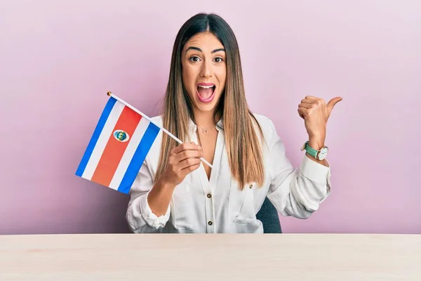 Jovem Hispânica Segurando Bandeira Costa Rica Sentado Mesa Apontando Polegar — Fotografia de Stock