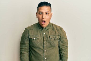 Gündelik kıyafetler giyen genç latin adam şaşkınlık ve şaşkınlık dolu bir ifade, korku ve heyecan dolu bir yüz.. 